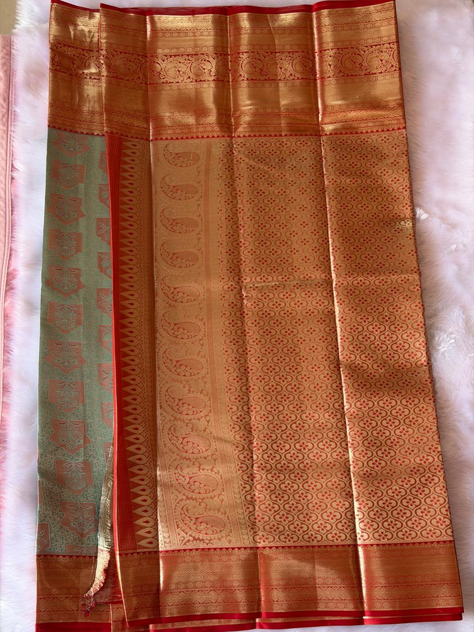 Gold zari peacock pallu detail of vibhuti green and kumkum red Kanchipuram polyester saree
